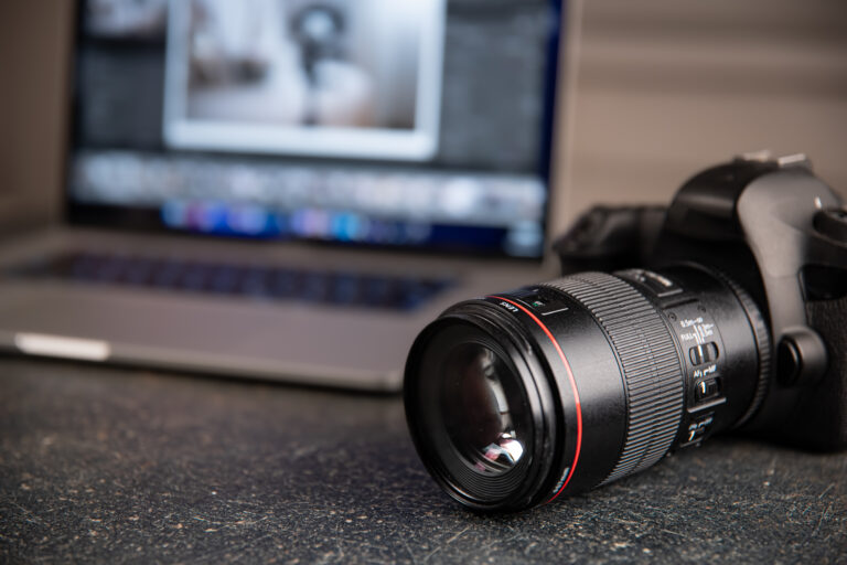 Digital professional camera on the table near the laptop close up