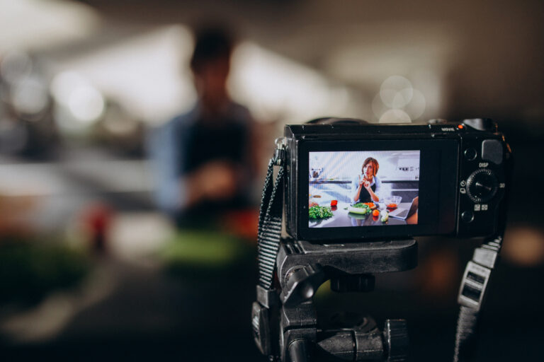 Young woman videoblogger cooking at the kitchen and filming
